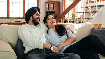 A man and woman laughing on the couch together.