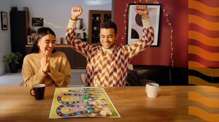 Two young adults play a board game at home.