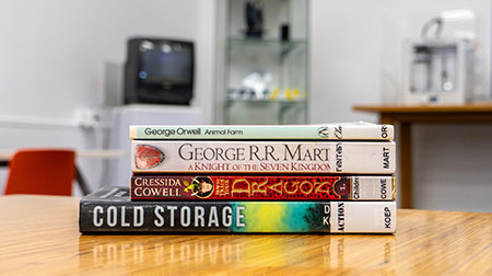 A small stack of books in front of a TV screen.
