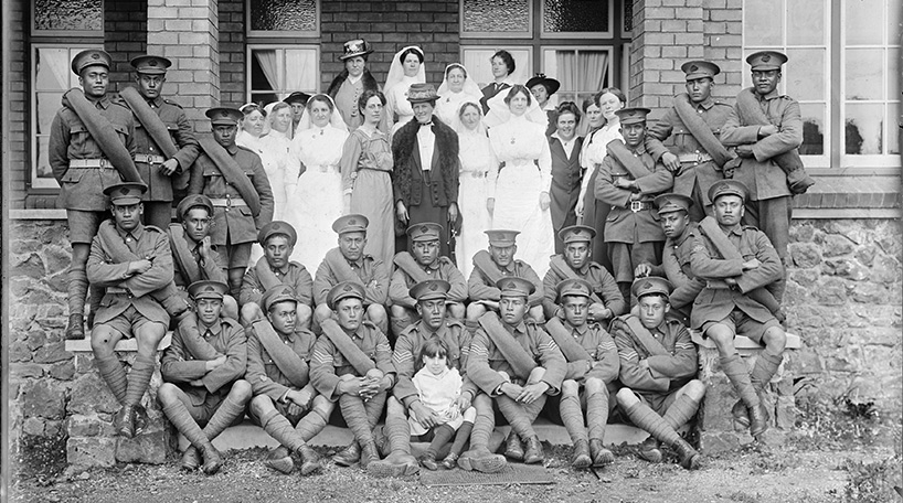 A black and white photo of nurses with soldiers in front of a building. This is part of the Auckland Council Libraries heritage collections.