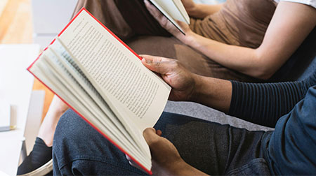 Two people reading books beside eachother.