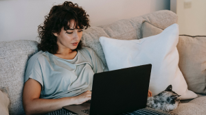 Woman watching a movie on her couch with a cat at her side