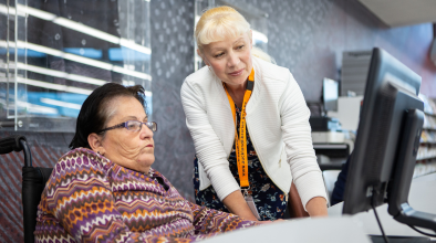 Photo of a librarian helping a customer on a computer