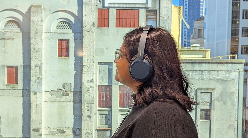 Man wearing headphones while looking at an artwork.