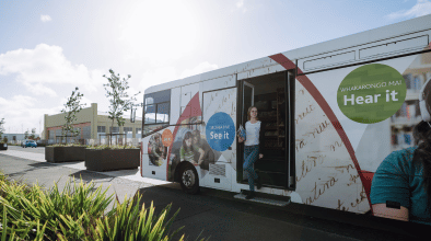 Photo of a customer leaving a mobile library bus with a pile of books to borrow.