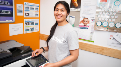 Photo of a woman smiling next to a library printer