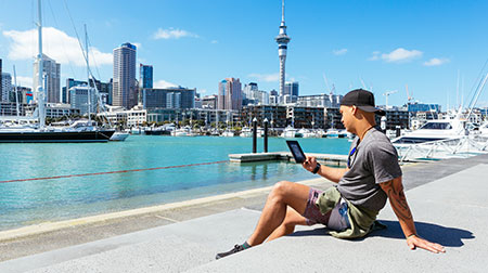 A man reading view a view of Auckland marina and city on a sunny summer day.