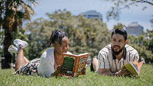 Two people reading books outdoors.