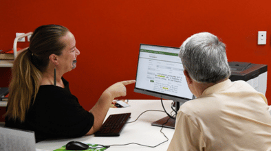 Photo of a research librarian assisting a customer in front of a computer.