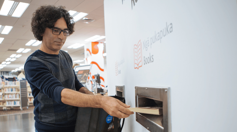 A library-user places a book into a return slot.