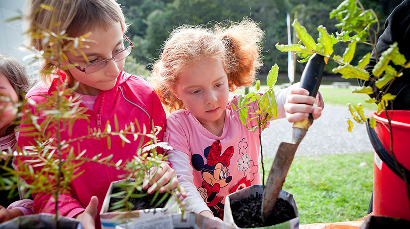 Kids focused on gardening activity outside a library