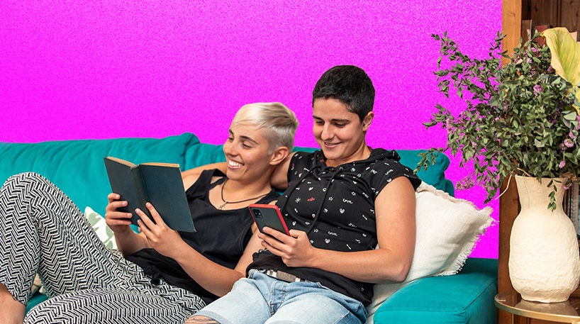 Two people reading together while cuddling on the sofa.