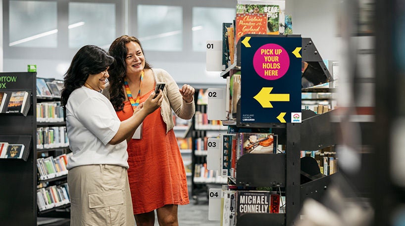 Staff and customer looking at mobile phone at the holds pick-up area.