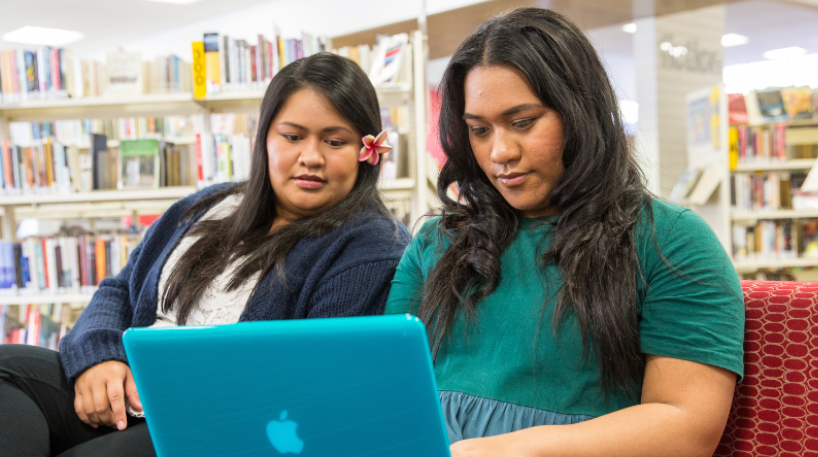 Two young women looking at a laptop inside the library