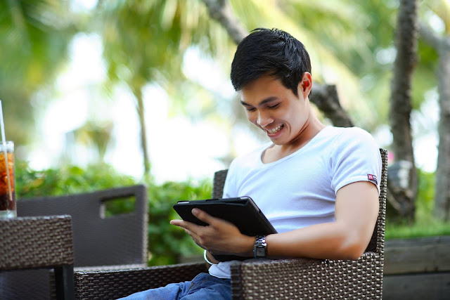A young man reading on an iPad in a garden