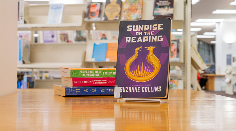 A stack of three books beside a front-facing book titled 'Sunrise on the Reaping'.
