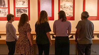 Five people facing away from camera looking over items in a display case