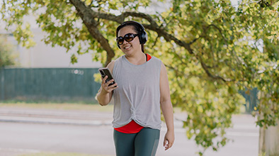 Woman using headphones and mobile phone while walking