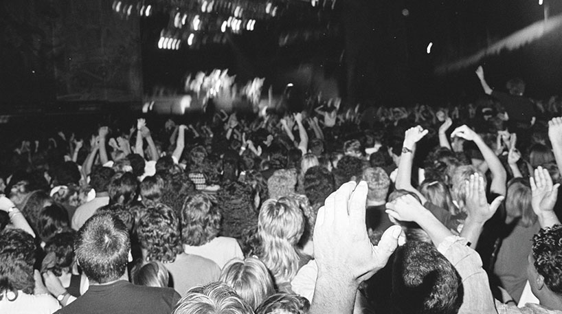Hands raised in a black and white photo of a crowd at a music event.