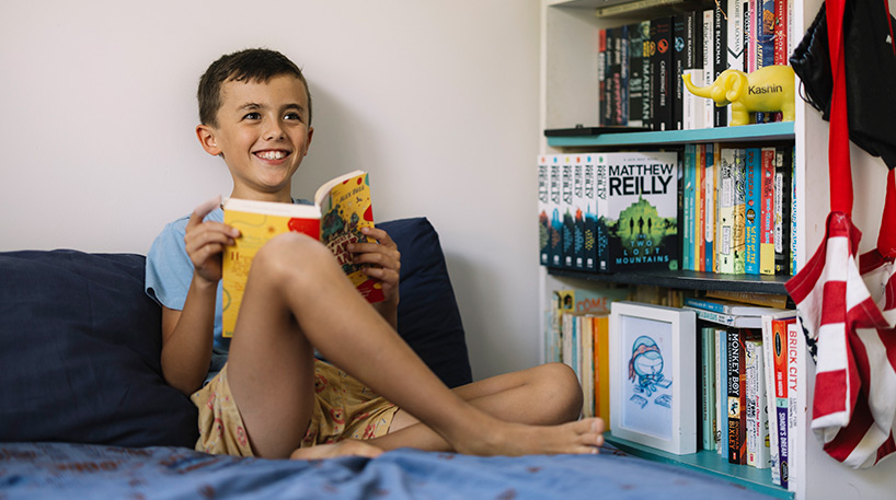 Smiling child enjoys cosy reading at home