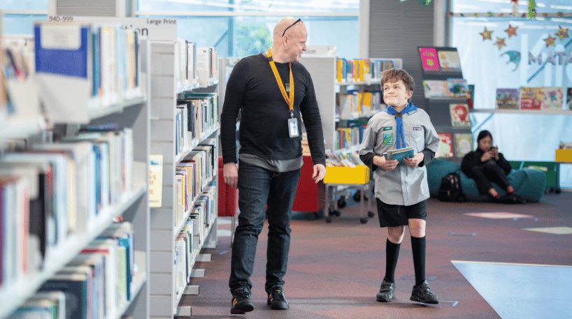 Librarian assisting a young customer at a library.